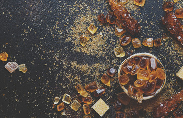 Sweet food background, assorted white and brown sugar on a dark background, top view