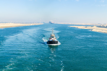 Ship's  convoy with cargo vessel container ship passing through Suez Canal, in the background - the Suez Canal Bridge, also known as Al Salam Bridge, Suez Canal, Egypt