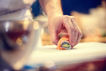 Japanese chef at work preparing delicious sushi roll