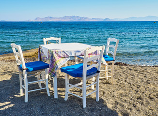 A table with chairs of a greek tavern near the sea in a beach of Kos island, Greece.
