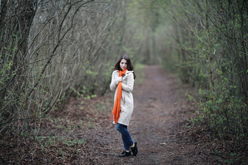 Naklejka na ściany i meble young woman in a trench coat walks in autumn park