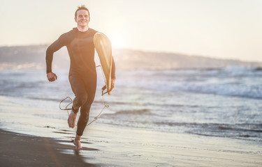 Fototapeta na wymiar Surfer running on the beach