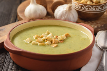 Broccoli cream soup with croutons on wooden background.