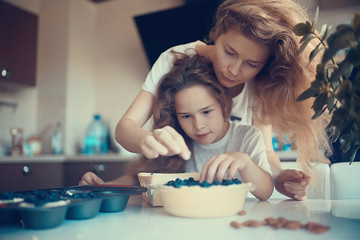 mother and daughter prepare a pie / home mom and daughter in kitchen bake a blueberry pie, the...