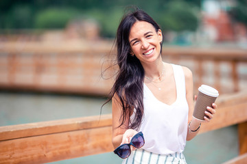 Happy young urban woman drinking coffee in european city.