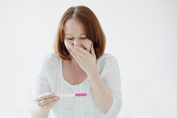 Happy young woman looking at positive pregnancy test