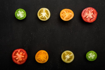 Colored tomatoes cut in half at the top and bottom of the frame. Fresh vegetables, copy space