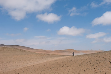 Fototapeta na wymiar The motorcyclist rides away in the desert. Peru, Ica