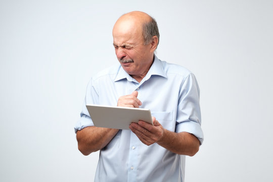 Senior caucasian man is disgusted by what he sees on a tablet device.