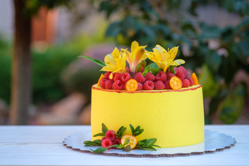 beautiful yellow cake with raspberry berries and live lilies