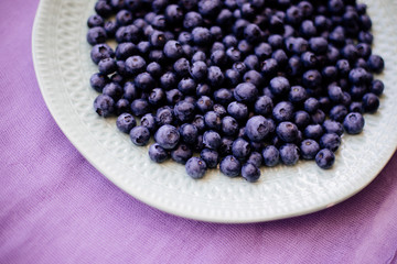 Blueberries in a plate on a table with a colored cloth.