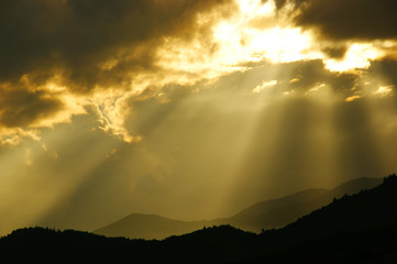 clouds with sunbeams. silhouettes of mountains and clouds at dawn