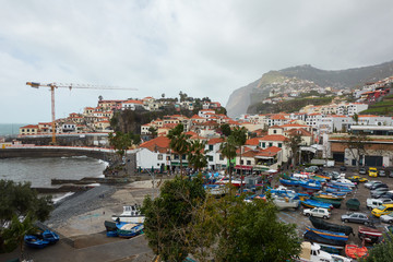 View of Câmara de Lobos in Madeira with Cape Girão on the background and boats at the marina