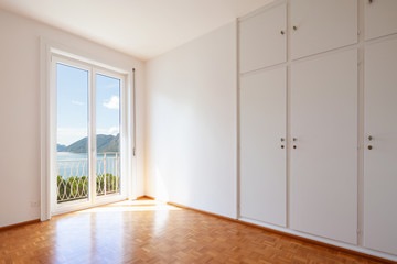 White room with large windows overlooking the lake