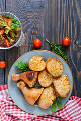 Tasty stuffed chicken legs with salad of fresh vegetables on a wooden background. Top view. Rolls with chicken and vegetables