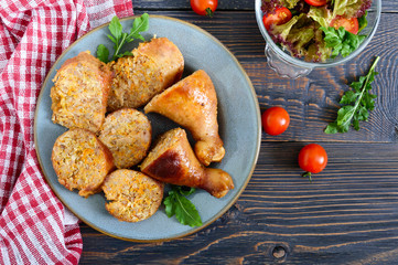 Tasty stuffed chicken legs with salad of fresh vegetables on a wooden background. Top view. Rolls with chicken and vegetables