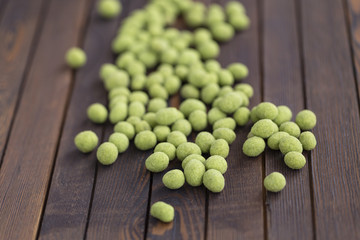 Peanuts with wasabi on wooden background, snack. Close up.