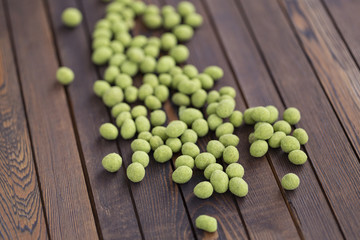 Peanuts with wasabi on wooden background, snack. Close up.