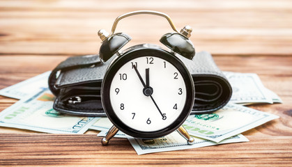 Alarm clock with wallet and money on the table. Business concept.