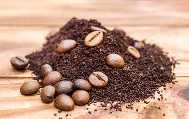Heap of ground coffee and coffee beans on wooden table.