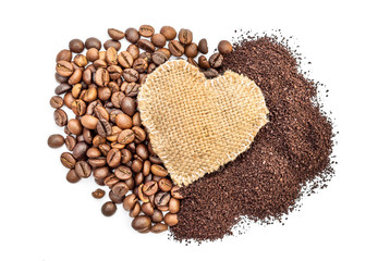 Burlap heart on pile of ground coffee and coffee beans. Isolated on white.