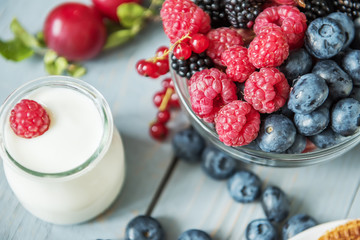 Yogurt and various berries on a light background. A useful delicious breakfast
