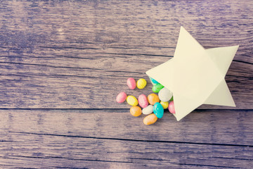 Sweet multicolored candy pills in paper gift box in the shape of yellow star. Sweet magical...