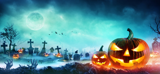 Obraz premium Jack O Lanterns And Zombie Hands Rising Out Of A Graveyard In Misty Night 