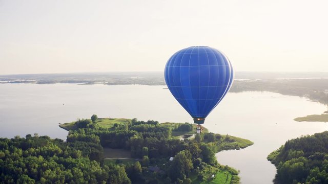 Hot Air Baloon Drifting Above Lake and Forest Scenery, Aerial View