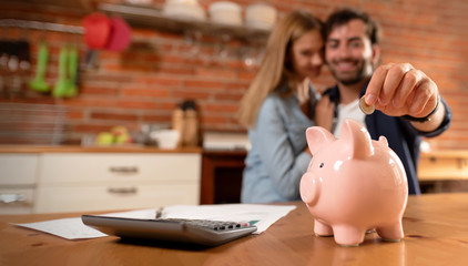 Happy couple inserting coin in piggybank