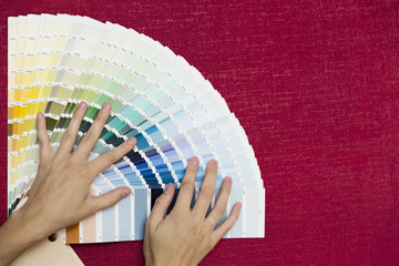 Home improvement. Beautiful women choosing a color from color palette. Renovating a room.