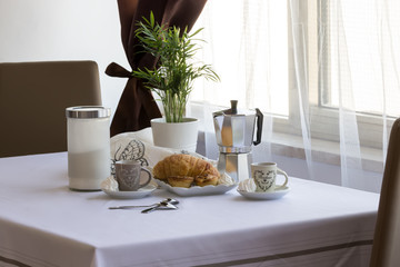 Italian breakfast: coffee, croissants, pasticiotto leccese, moka on the table, white background in the kitchen