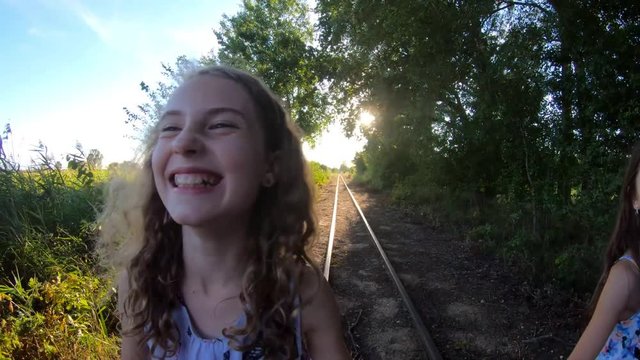happy young girls are walking along the railroad tracks