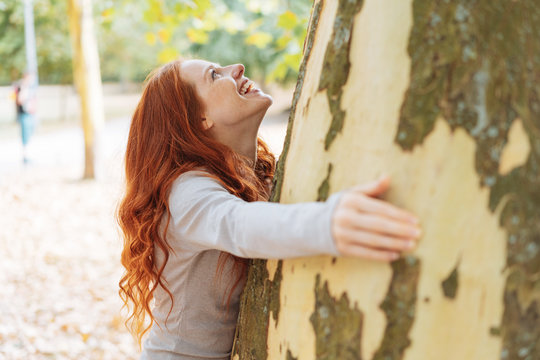 Happy young woman hugging a large tree