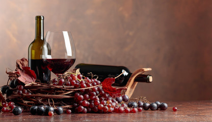 Red wine and fresh grapes with dried up vine leaves.