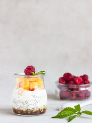 Vanilla chia seeds pudding in glasses with fresh raspberries and peaches. Healthy dessert breakfast.