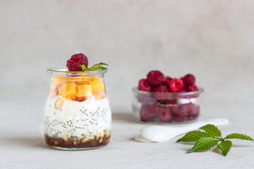 Vanilla chia seeds pudding in glasses with fresh raspberries and peaches. Healthy dessert breakfast.