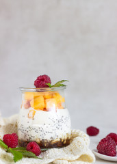 Vanilla chia seeds pudding in glasses with fresh raspberries and peaches. Healthy dessert breakfast.