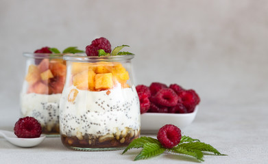 Vanilla chia seeds pudding in glasses with fresh raspberries and peaches. Healthy dessert breakfast.