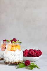 Vanilla chia seeds pudding in glasses with fresh raspberries and peaches. Healthy dessert breakfast.