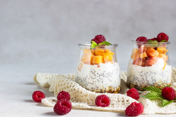 Vanilla chia seeds pudding in glasses with fresh raspberries and peaches. Healthy dessert breakfast.