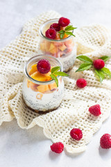 Vanilla chia seeds pudding in glasses with fresh raspberries and peaches. Healthy dessert breakfast.