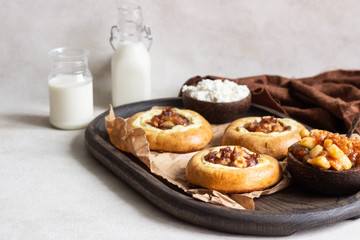Fresh homemade open yeast buns with cottage cheese and caramel apple (traditional Russian pastry vatrushka, round buns, curd tart) on light grey background. Sweet rolls. Selective focus. Rustic style.