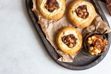 Fresh homemade open yeast buns with cottage cheese and caramel apple (traditional Russian pastry vatrushka, round buns, curd tart) on light grey background. Sweet rolls. Selective focus. Rustic style.