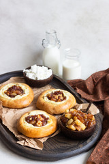 Fresh homemade open yeast buns with cottage cheese and caramel apple (traditional Russian pastry vatrushka, round buns, curd tart) on light grey background. Sweet rolls. Selective focus. Rustic style.