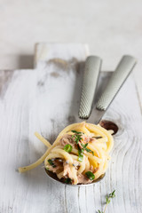 Spaghetti with tuna and arugula salad (rucola) on a grey plate