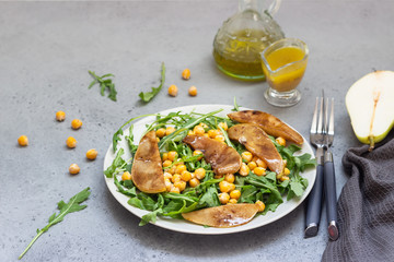 Healthy vegetable salad with spicy chickpeas, arugula and pear on a natural stone background. Delicious balanced food concept. Vegetarian food.