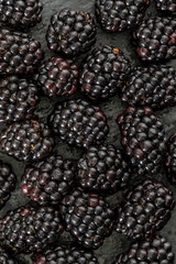 Delicious fresh and ripe blackberries and reddish garnet. With drops of water. On textured background in black color.