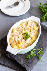 Baked mac and cheese, american style macaroni pasta with cheesy sauce, parsley and crunchy breadcrumbs topping, in portioned ceramic form.