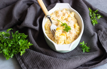 Baked mac and cheese, american style macaroni pasta with cheesy sauce, parsley and crunchy breadcrumbs topping, in portioned ceramic form.